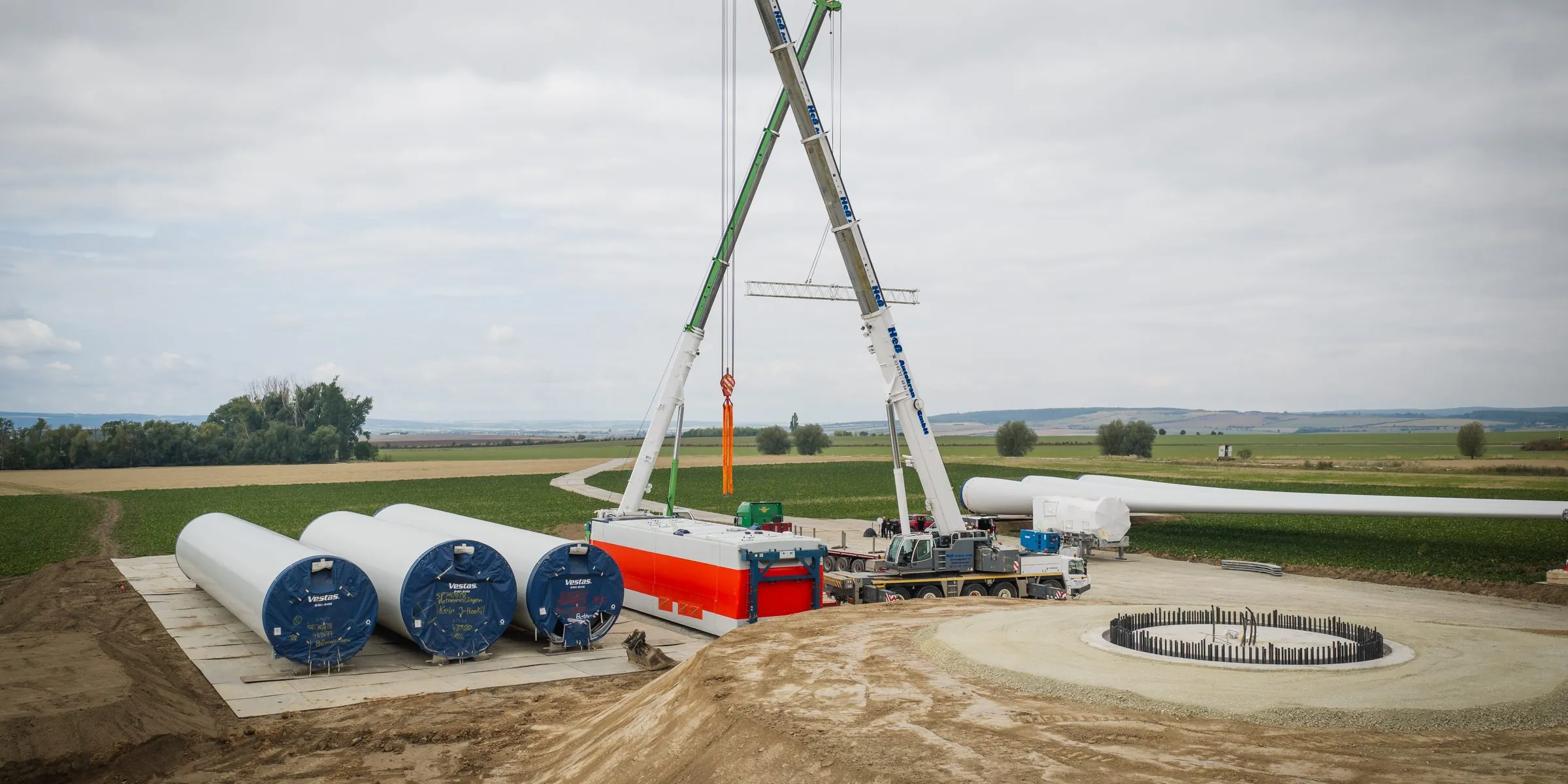 Zwei Autokrane mit gekreuzten Auslegern über dem Fundament einer Windkraftanlage