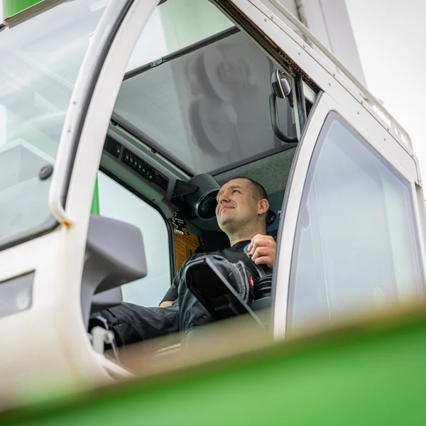 Lächelnder Kranfahrer in der Kabine seines Autokrans