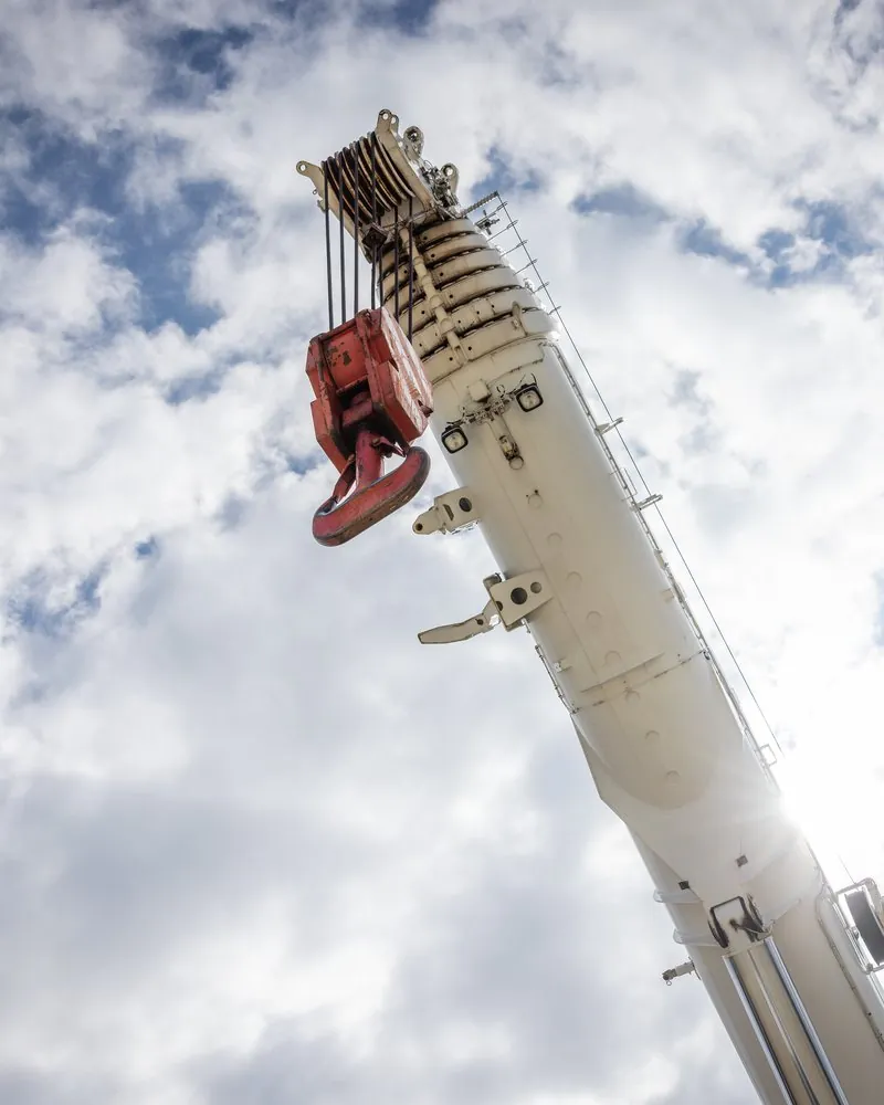 Autokranausleger mit Hakenflasche vor Wolken, von unten fotografiert