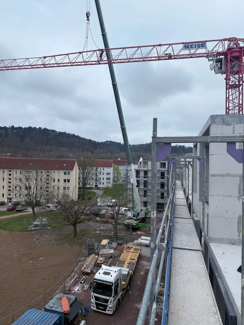 Autokran demontiert einen roten Baukran zwischen Wohnhäusern