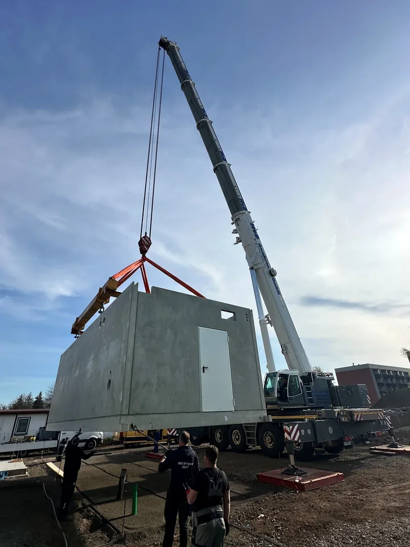 Autokran hebt das Betongehäuse eines Blockheizkraftwerks