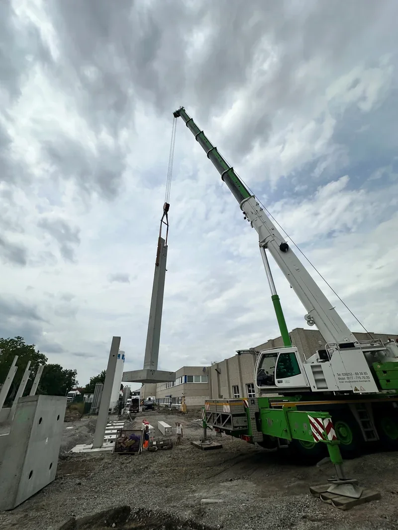 Autokran stellt eine Betonstütze mit Fundamentfuß auf