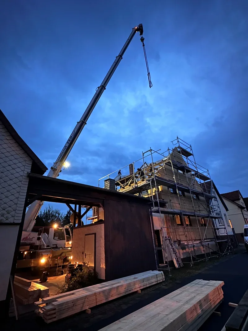 Citykran am Abend über einem Holzbau mit Gerüst
